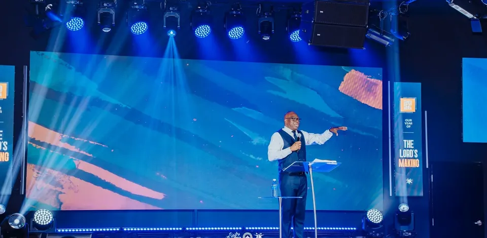 Le pasteur David Adeosun parle au lutrin devant le mur LED à Kingdom Stars Assembly, Guelph